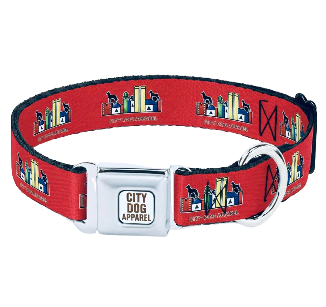 A red dog collar with a silver metal buckle and D-ring, featuring a repeating pattern of a city skyline with a dog silhouette and the text 'City Dog Apparel'.
